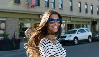 Mujer feliz con pelo largo sedoso sonriendo mientras cruza la calle