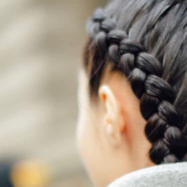 A model with dark brown hair in two thick braids